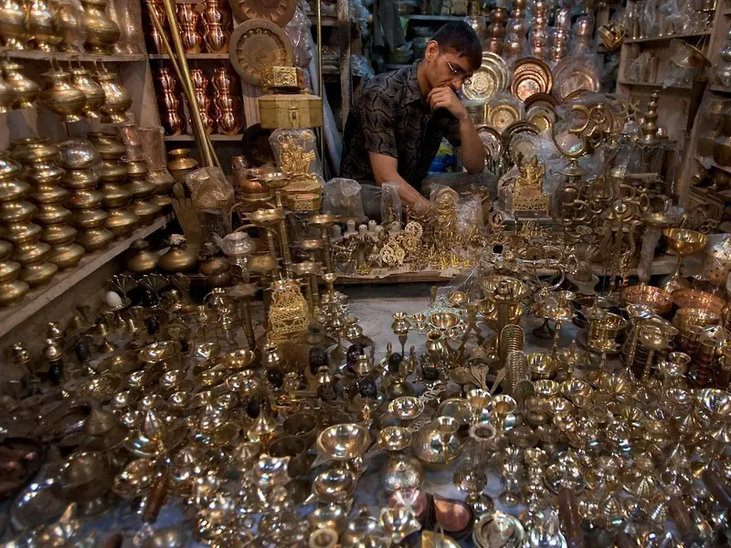 A brassware stall stacked with polished brass pots, lamps and plates in a Varanasi market