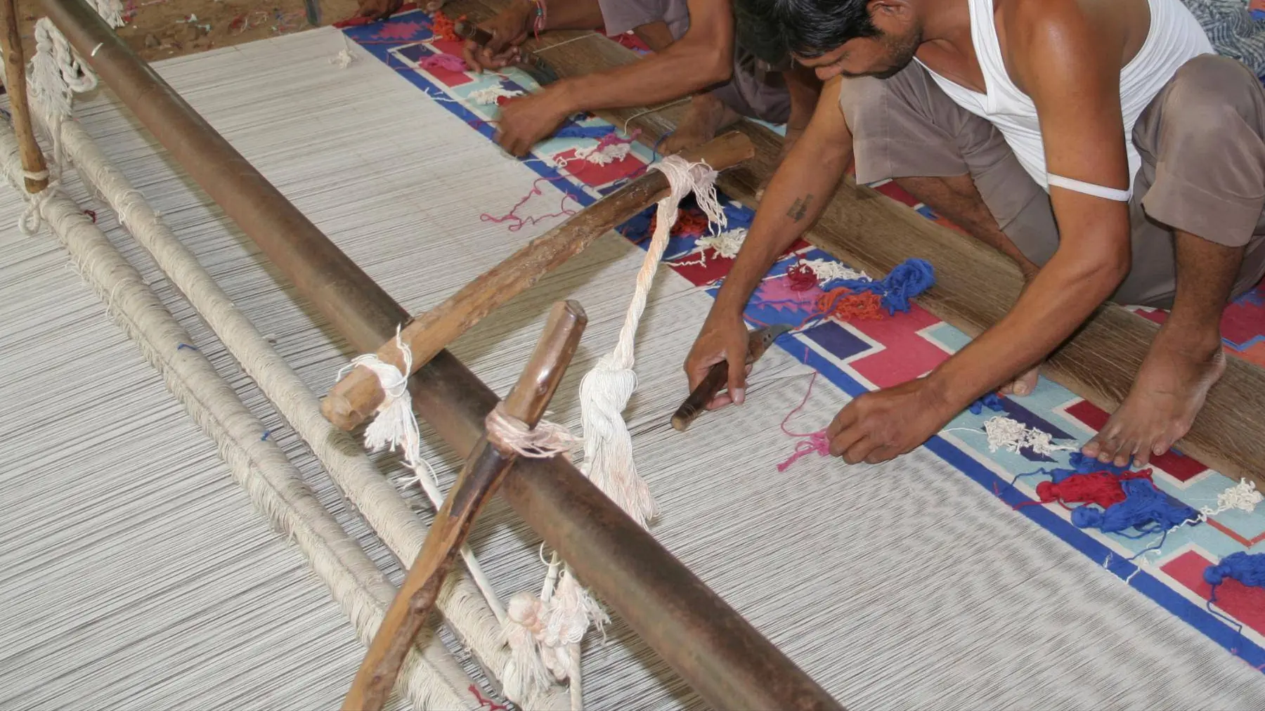 Artisans weaving a flat-woven carpet on a floor loom near Jaipur